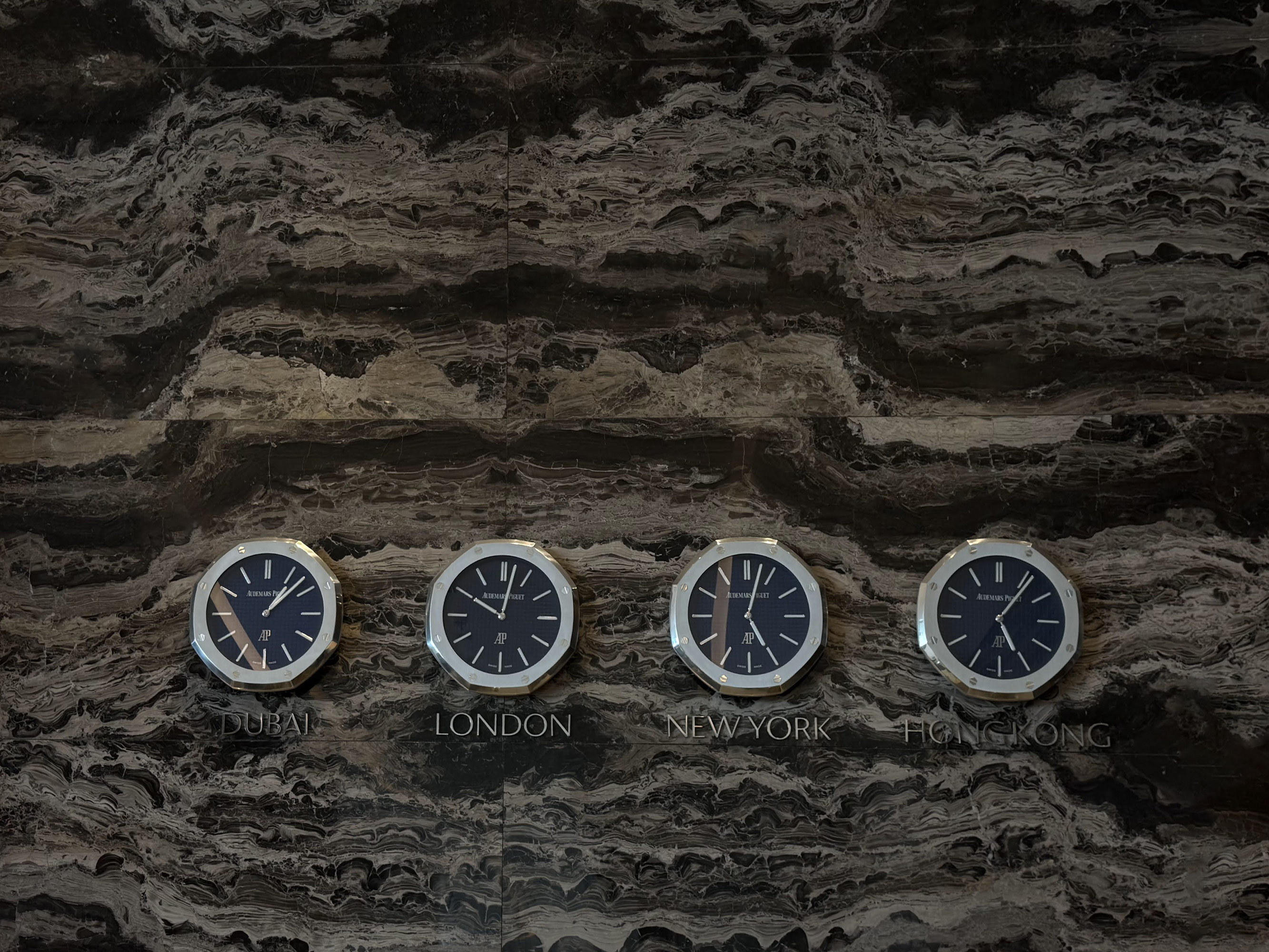 Four clocks on the veined marble, the hours of other cities
