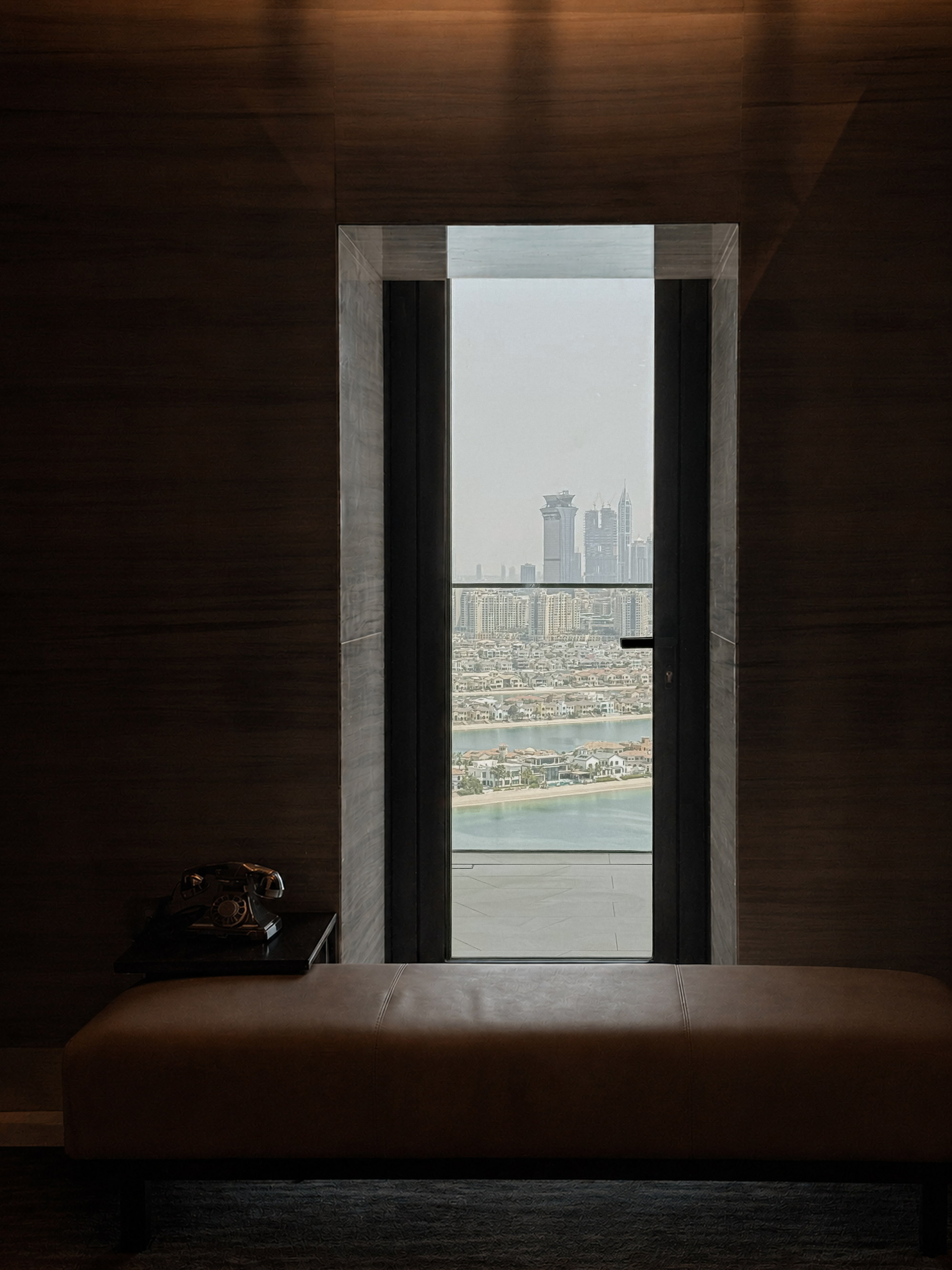 A window in shadow, the Palm and the city held in its frame