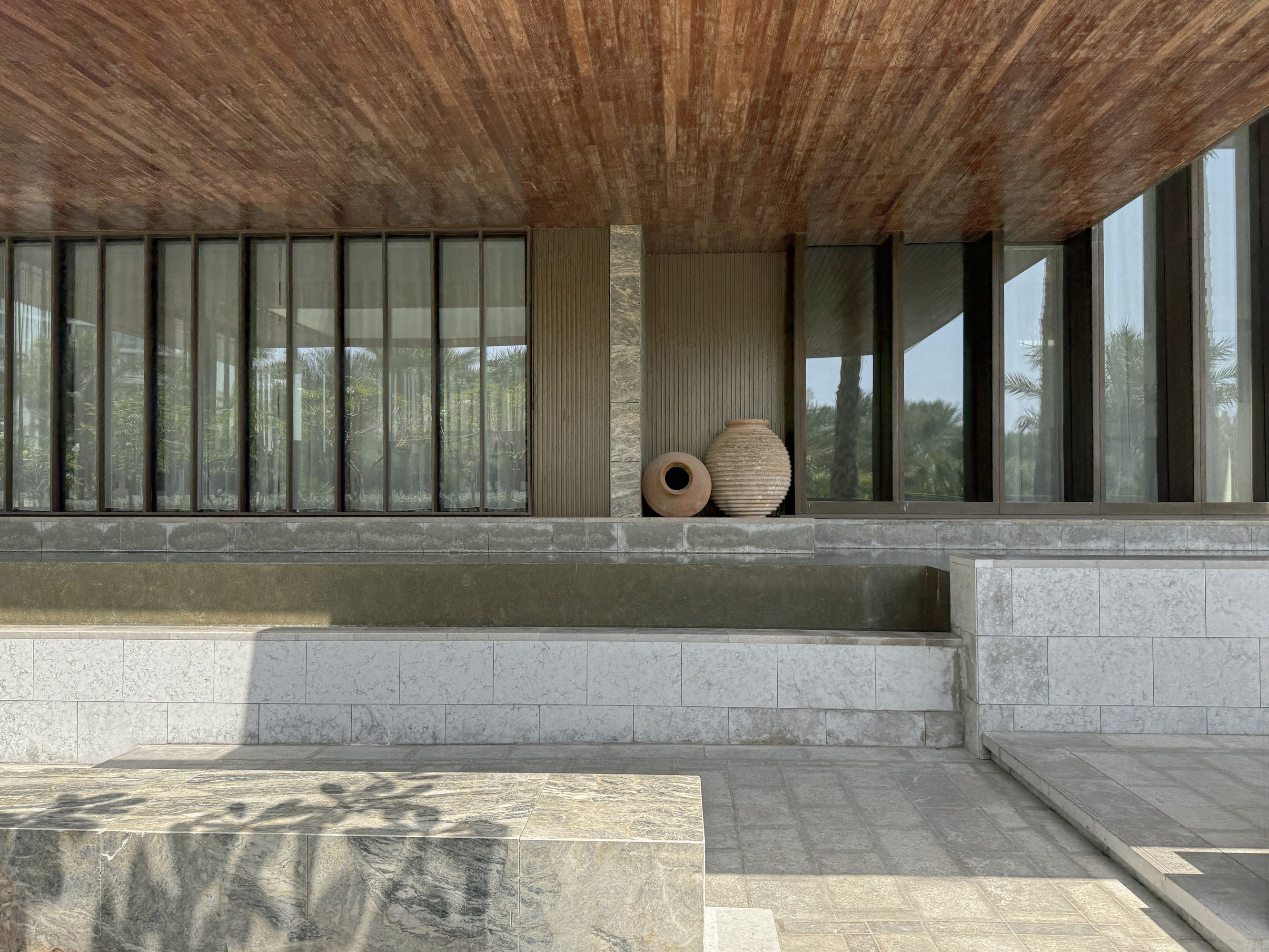 The terrace at midday, earthen vessels beneath the timber soffit