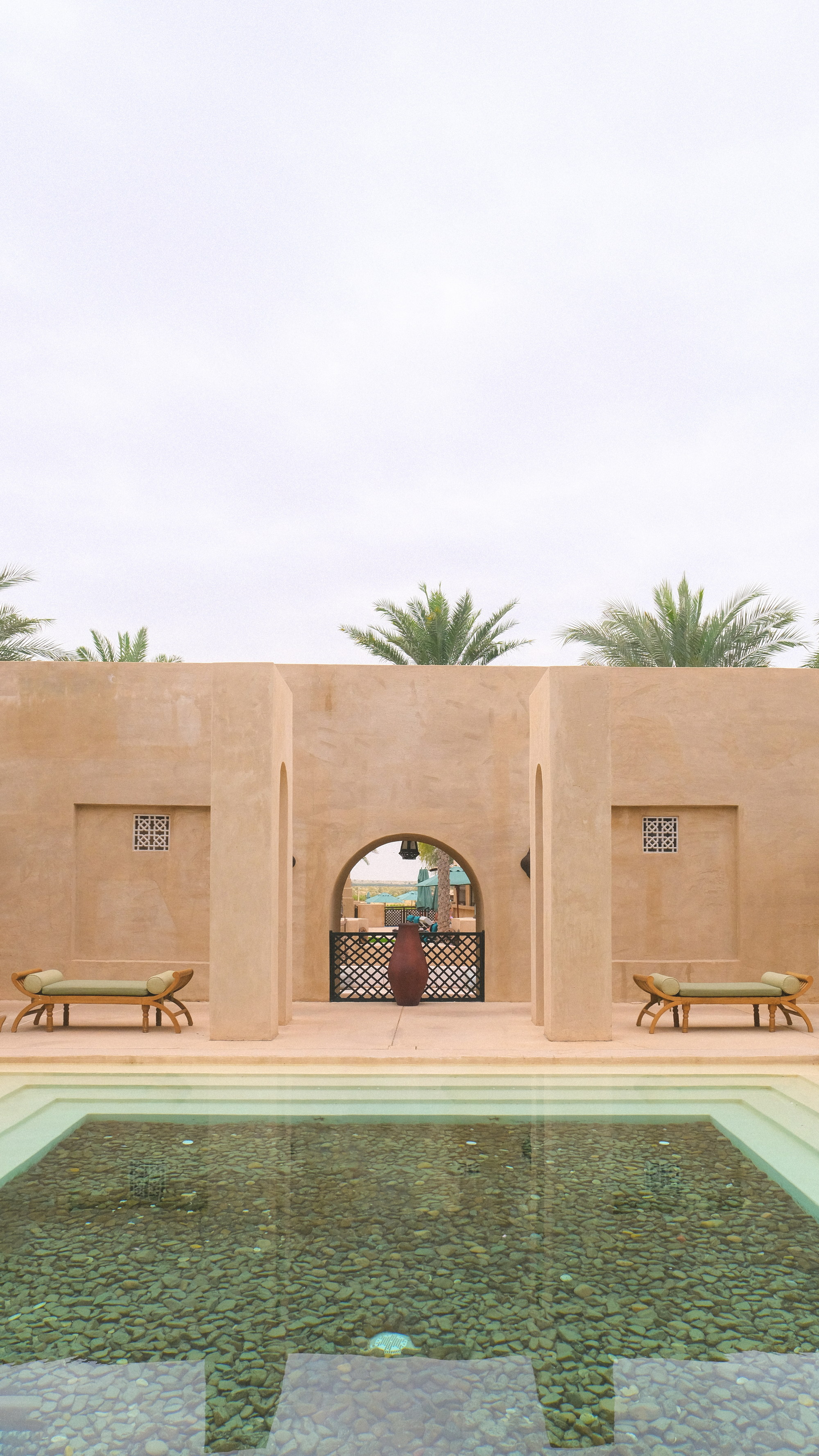 The spa courtyard at Bab Al Shams, two benches flanking the gate, the urn at centre