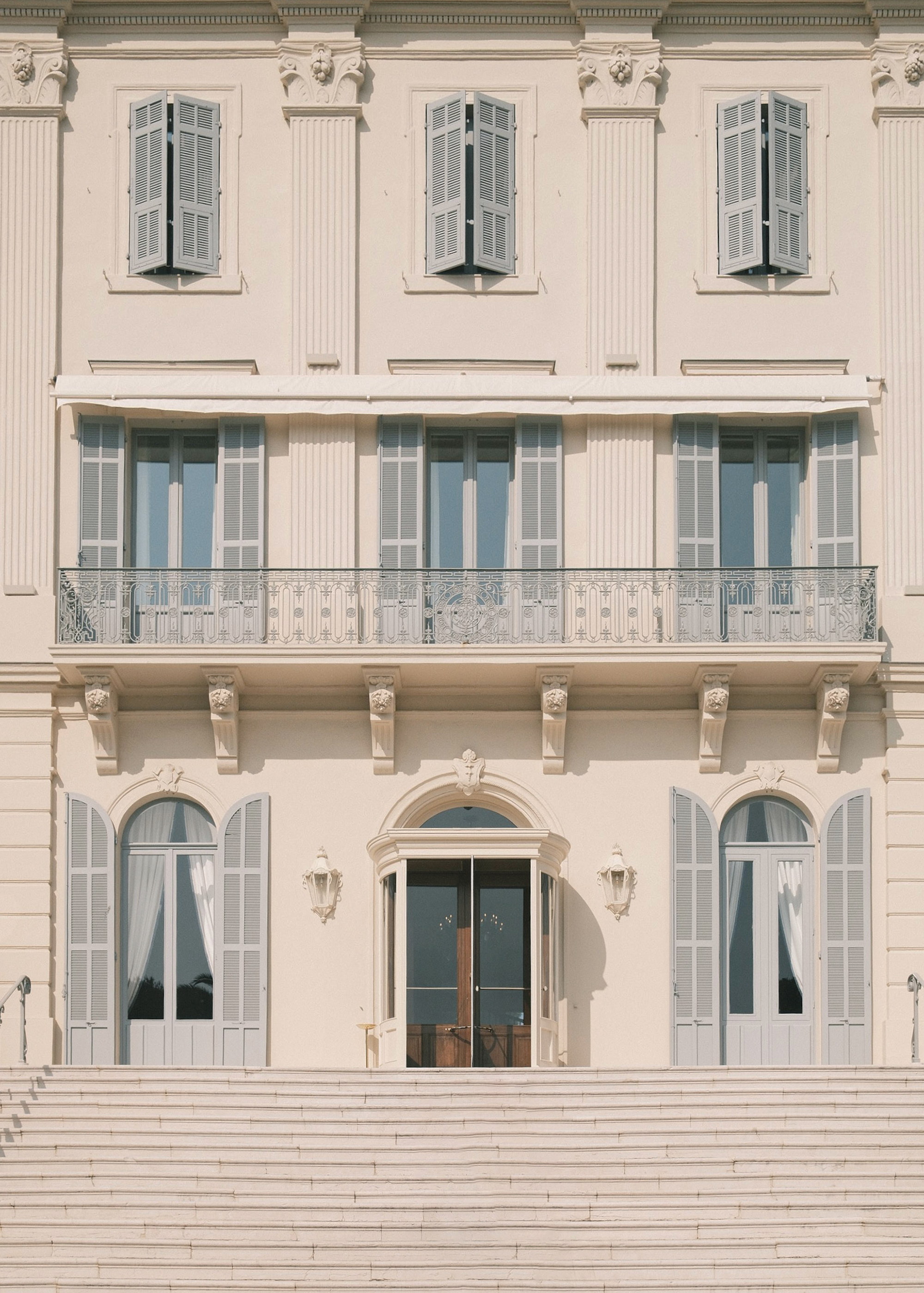 Facade read flat — shutters, corbels, ironwork in three registers
