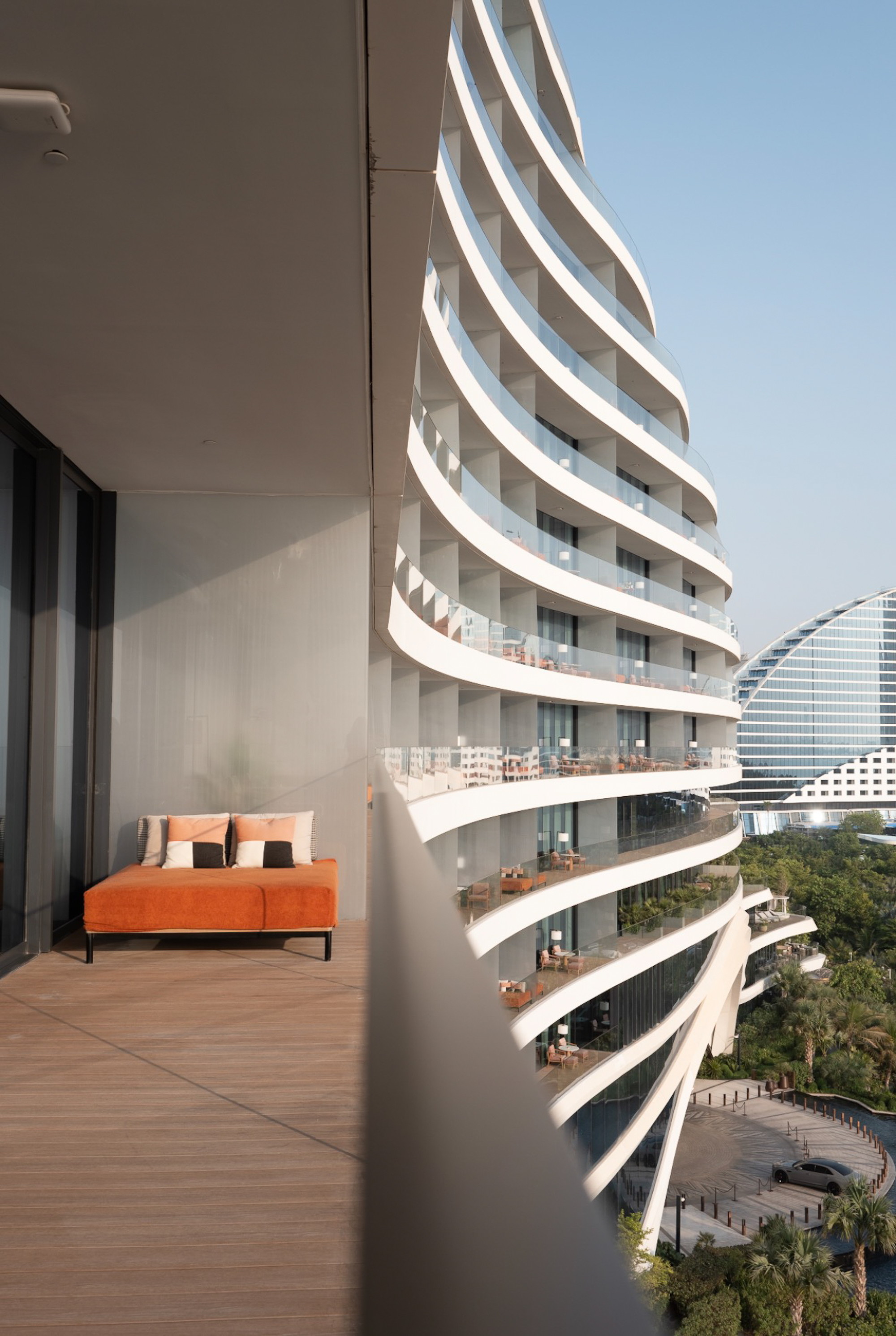 Balconies stacked and curving away, the wave of the neighbouring hotel beyond