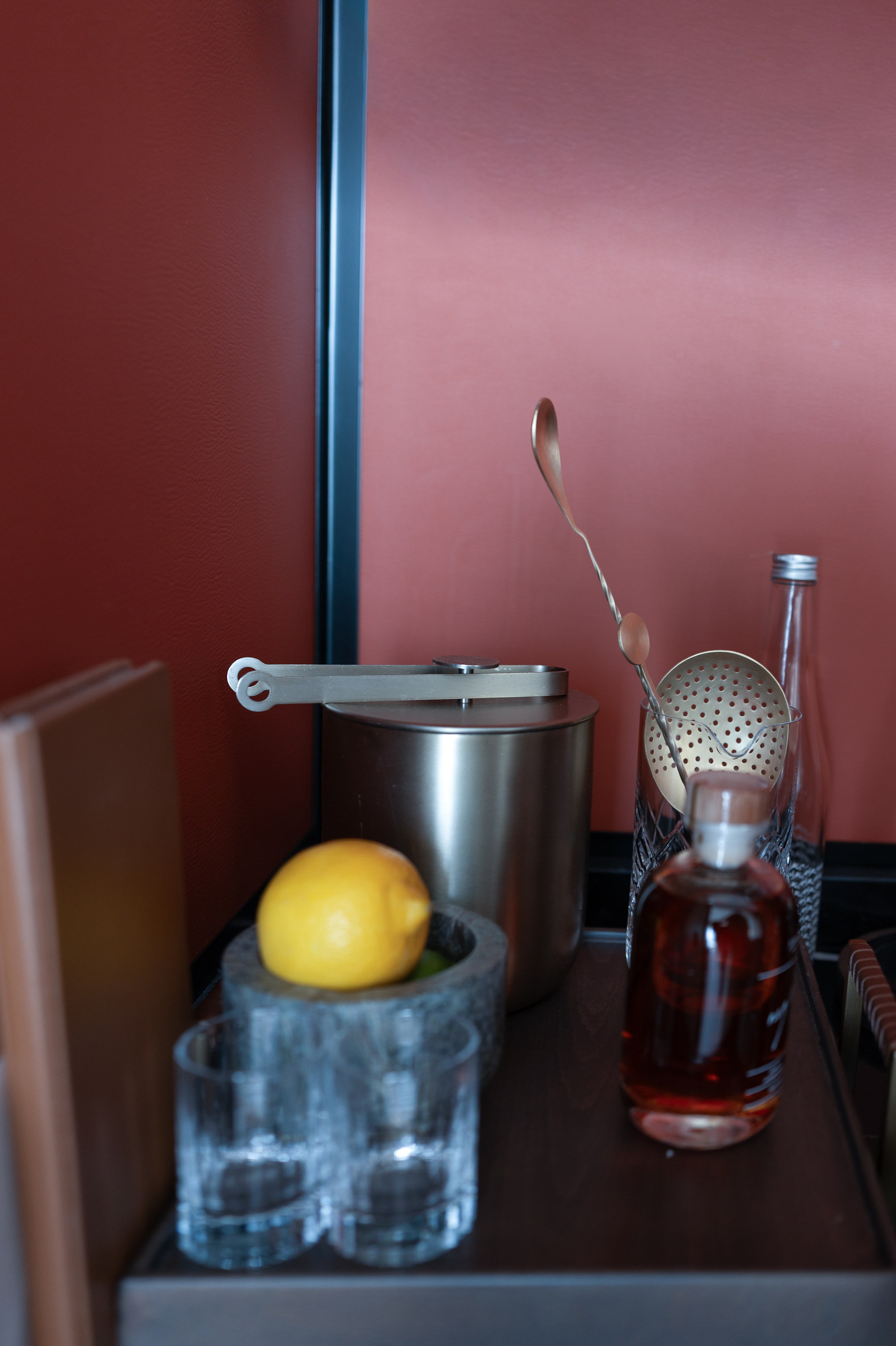 The bar corner, a lemon in the mortar, the decanter against red leather