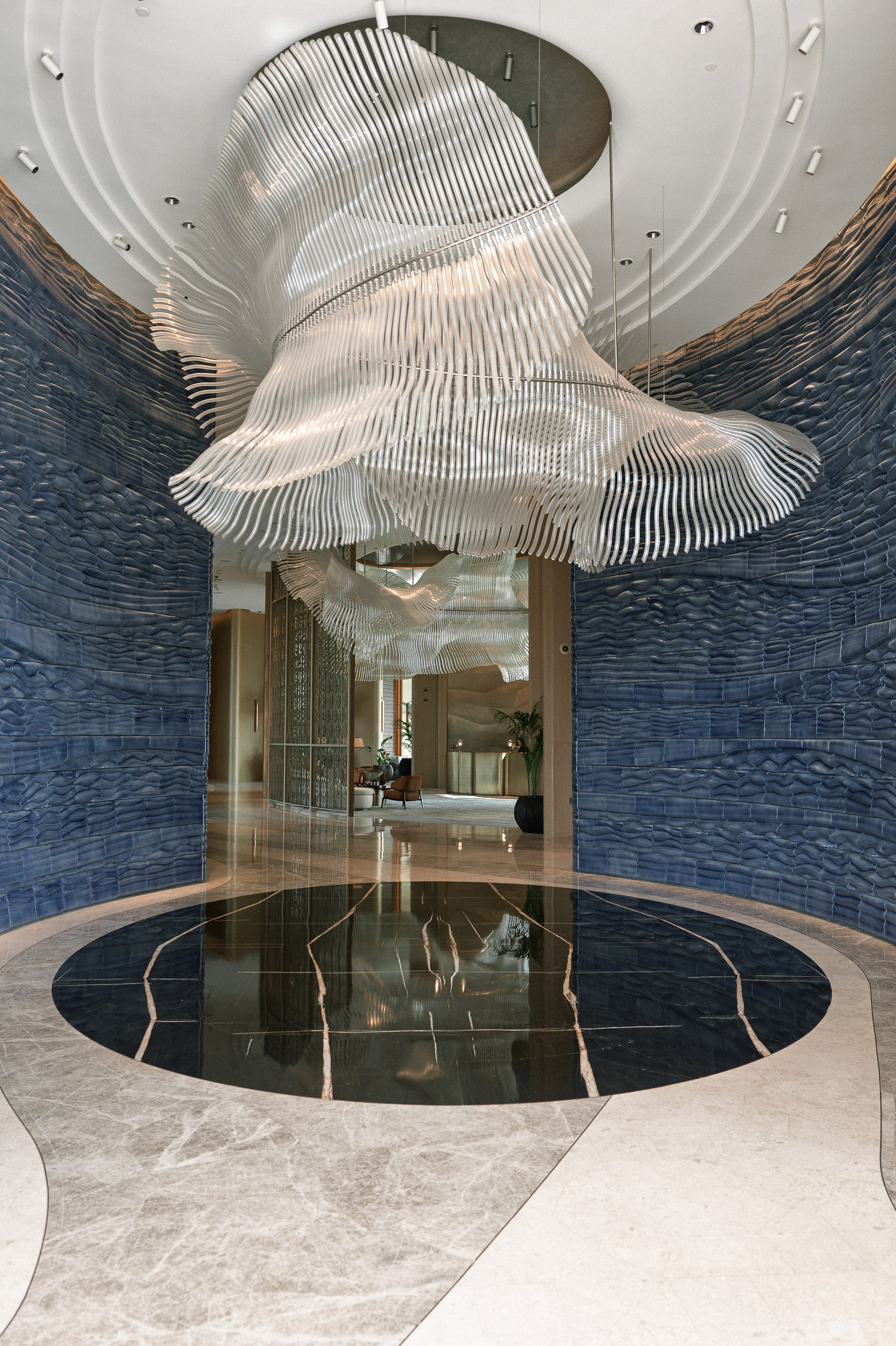 The lobby, a white sculpture suspended over the black marble circle, the blue walls curving away