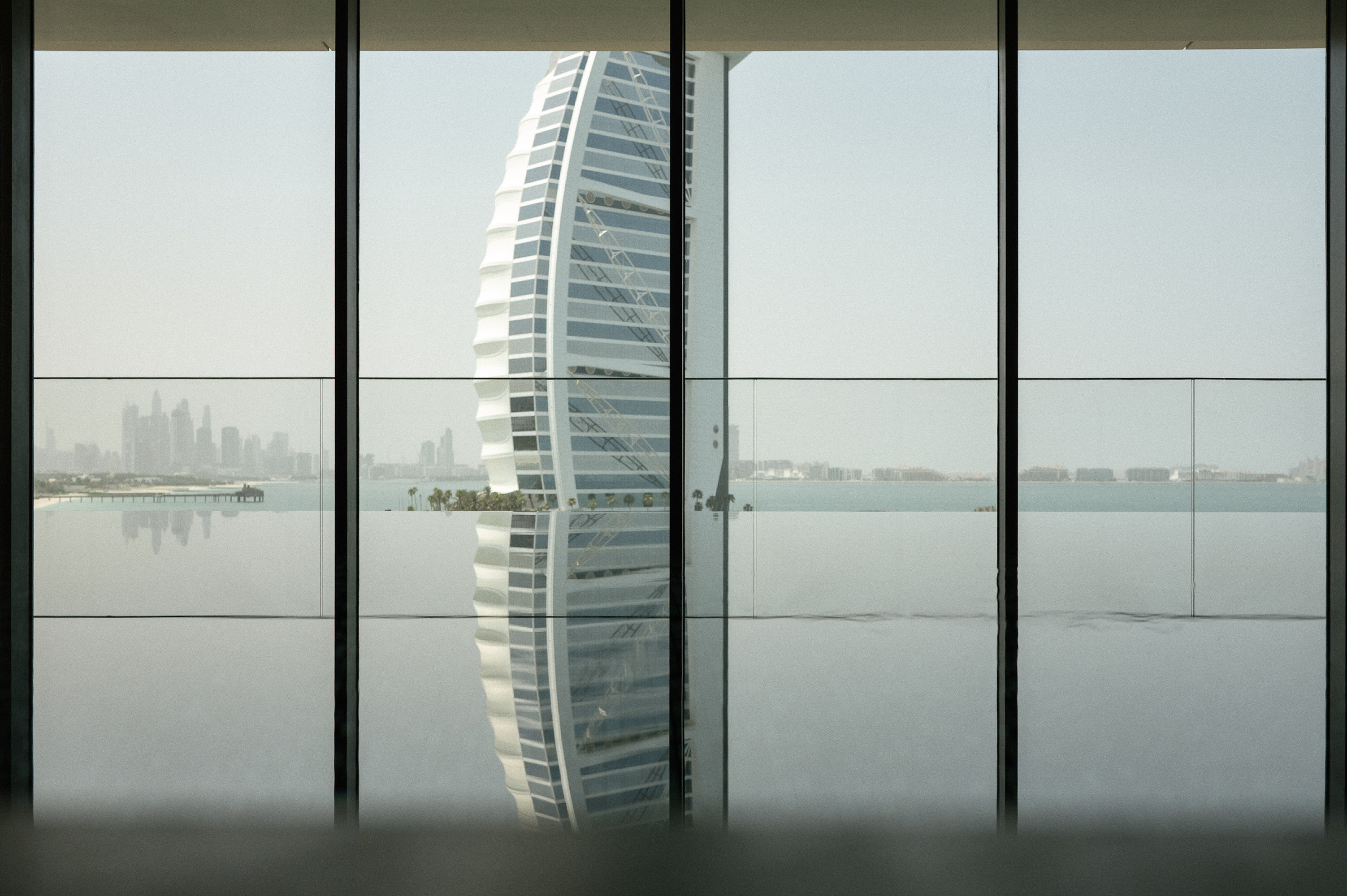 The infinity pool through the glazing, the Burj and its reflection held between the mullions
