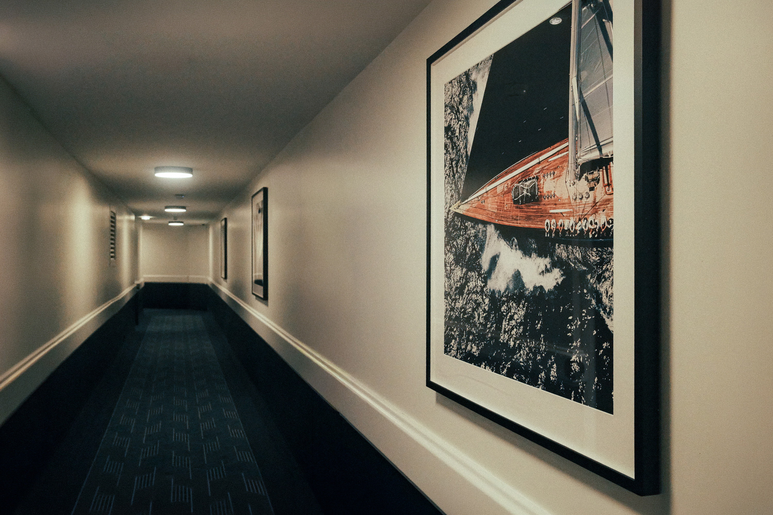 The corridor running away, a hull under sail framed on the wall