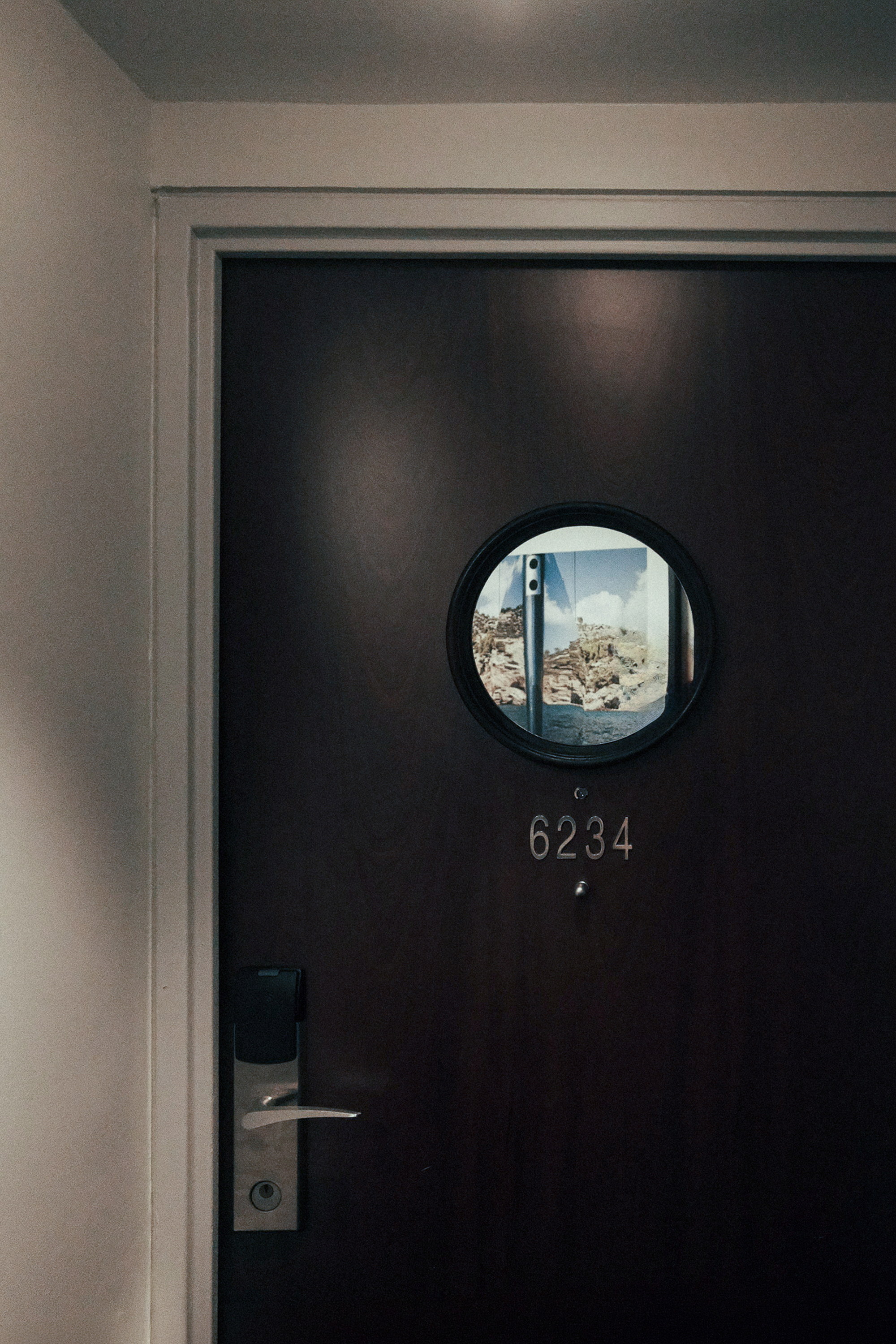 A porthole set into the door, a coastline standing inside it