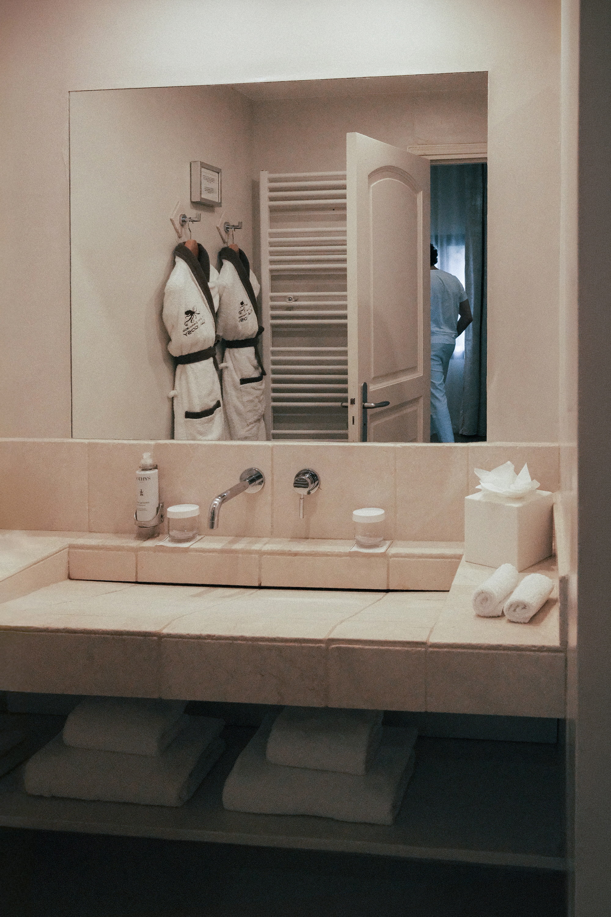 Two robes in the mirror, the door open to the room beyond