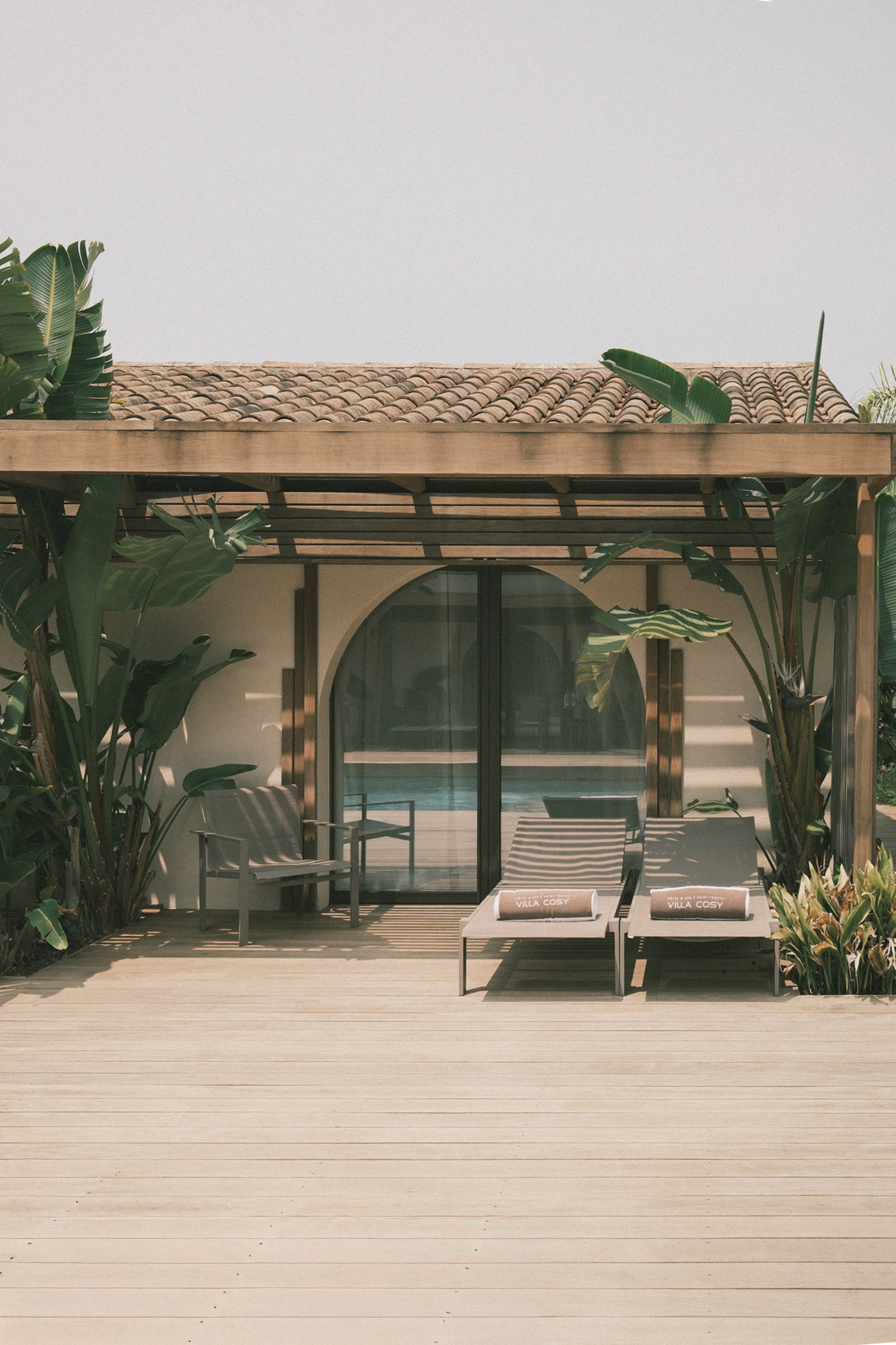 The arched threshold beneath the pergola, chaises turned to the water