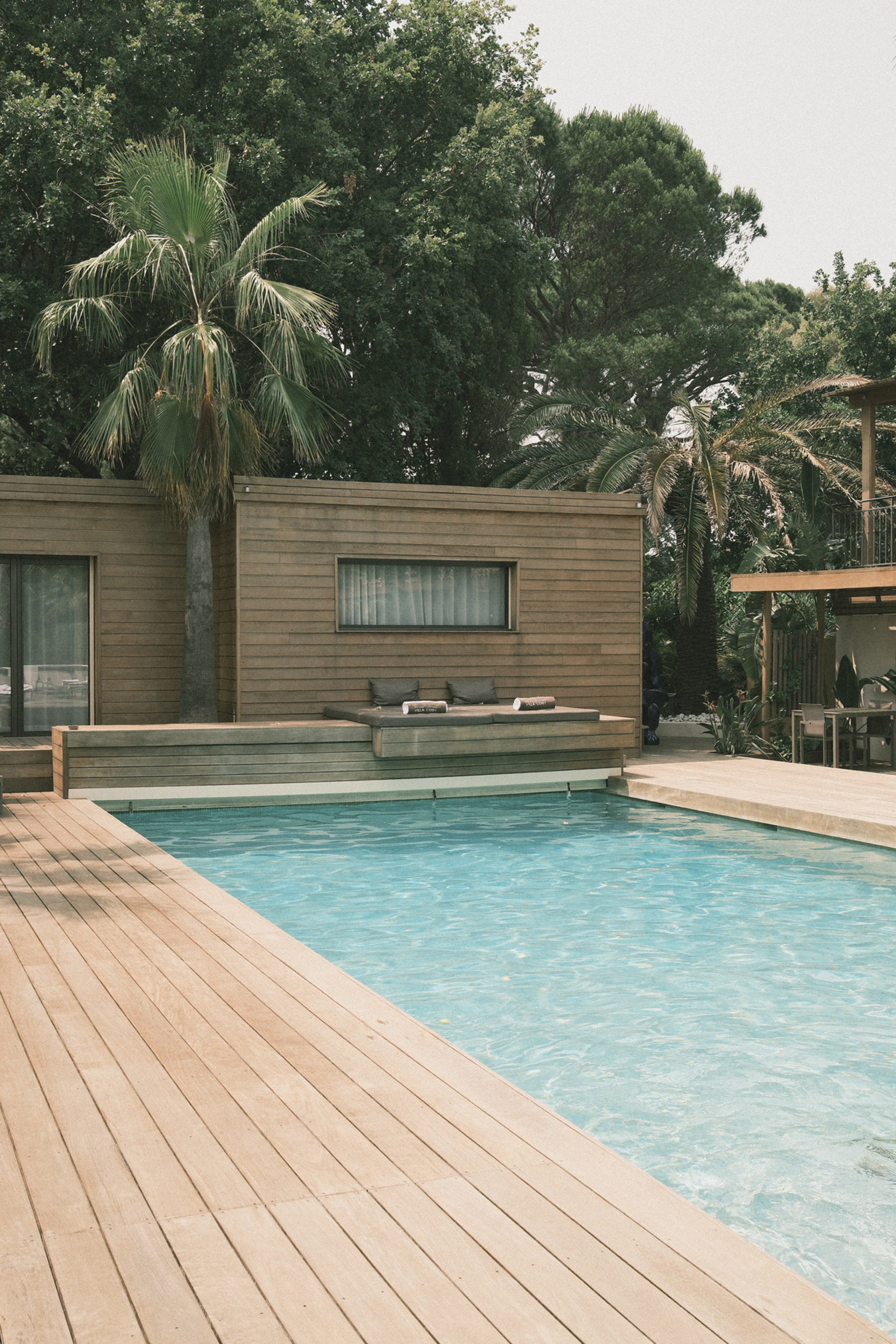 The pool's corner, a daybed set into the deck, palms closing in