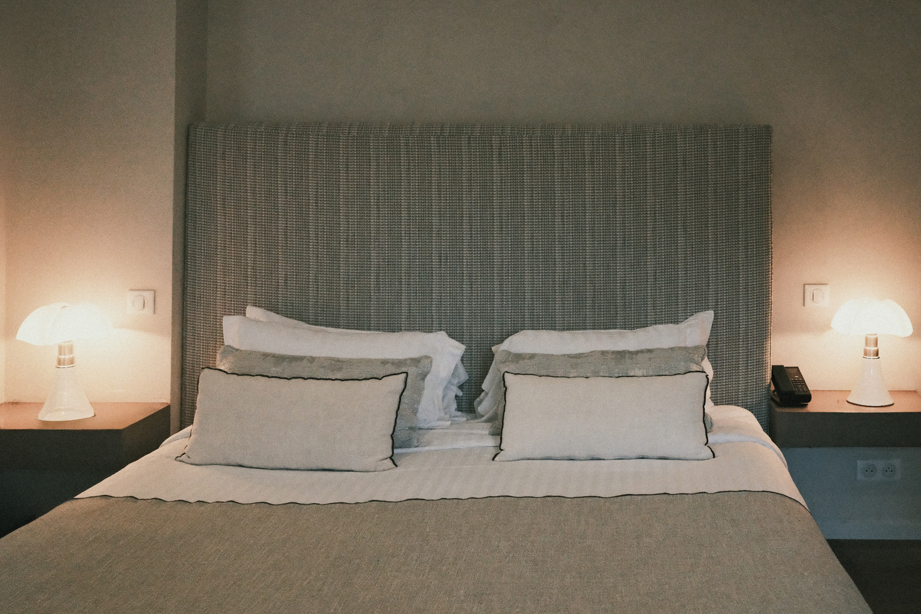 Two lamps lit at dusk, the bed dressed in linen